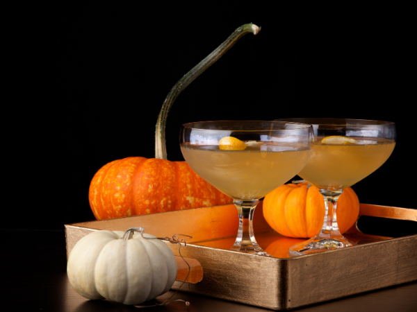 Two coup glasses on a tray surrounded by stacks of pumpkins